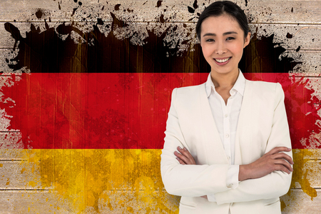 Smiling businesswoman looking at the camera against germany flag in grunge effectの写真素材