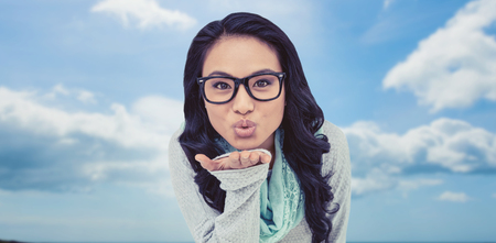 Asian woman blowing kiss to the camera against beach with blue skyの写真素材