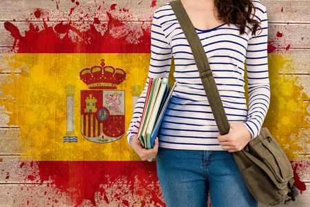 Mid section of man with should bag and files against spain flag in grunge effectの写真素材