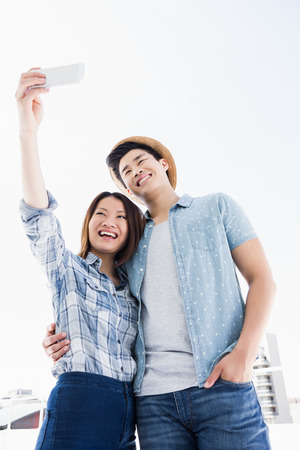 Happy young couple taking a selfie on smartphone outdoorsの写真素材