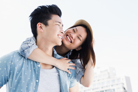 Young man giving a piggyback ride to woman outdoorsの写真素材