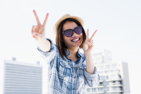 Happy young woman doing a v sign outdoorsの写真素材