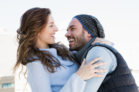 Happy young couple cuddling each other and smiling outdoorsの写真素材