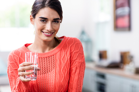 Portrait of happy young woman holding drinking glass at homeの写真素材