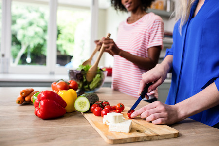 Midsection of female friends preparing food at table in kitchenの写真素材