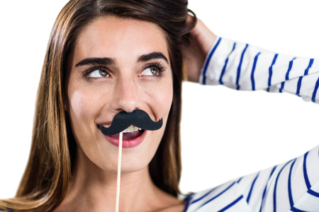 Smiling woman holding artificial mustache on white bckgroundの写真素材