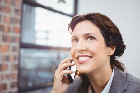 Close-up of happy young businesswoman looking away while talking on mobile phoneの写真素材