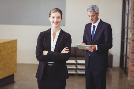 Happy businesswoman with male colleague standing in backgroundの写真素材