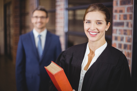 Portrait of happy female lawyer with businessman standing in backgroundの写真素材