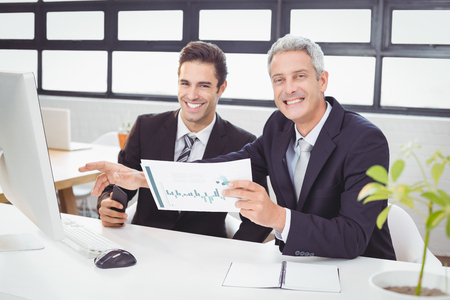 Portrait of business people working at computer desk in officeの写真素材