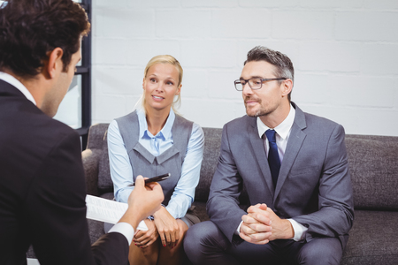Business people discussing while sitting on sofa in officeの写真素材