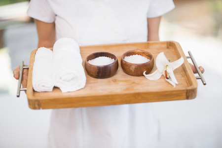 Midsection of female masseur holding tray with spa therapy productsの写真素材