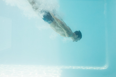 Side view of shirtless man swimming underwaterの写真素材