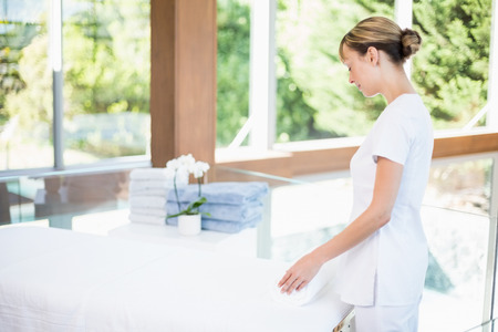 Female masseur rolling towel on massage table at health spaの写真素材