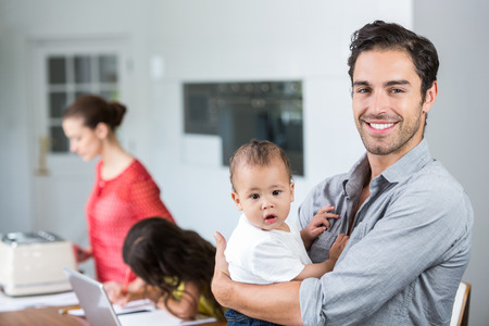 Portrait of smiling father carrying baby with daughter and mother at homeの写真素材