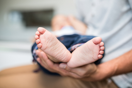 Midsection of father holding baby at homeの写真素材