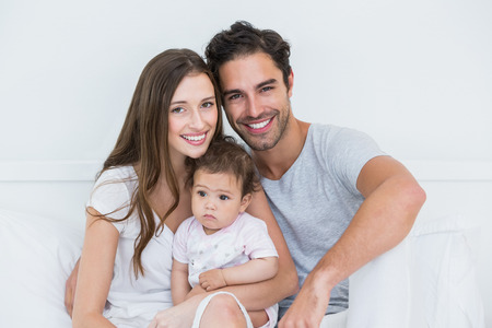 Portrait of happy couple with baby girl on bed at homeの写真素材