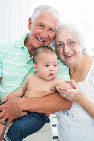 Portrait of smiling grandparents with baby at homeの写真素材