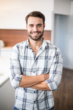 Portrait of confident man with arms crossed standing by kitchen counterの写真素材