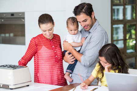 Smiling family with daughter studying at desk in homeの写真素材
