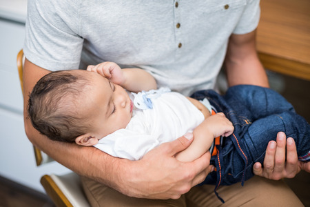 High angle view of father carrying sleeping baby at home