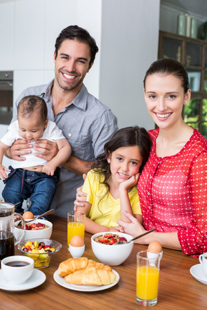Portrait of smiling family at breakfast table in homeの写真素材