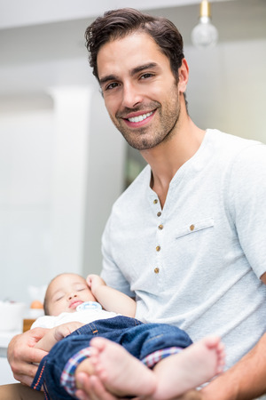 Portrait of smart father carrying baby at homeの写真素材