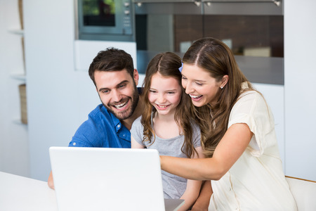 Family laughing while looking at laptop at homeの写真素材