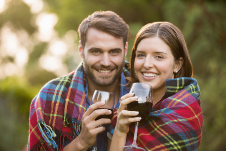 Portrait of smiling couple wrapped in blanket at parkの写真素材