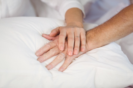 Cropped image of senior couple holding hands on pillowの写真素材