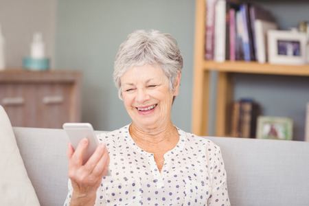 Senior woman holding mobile phone at home