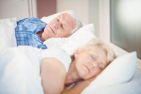 High angle view of senior couple sleeping on bed in roomの写真素材