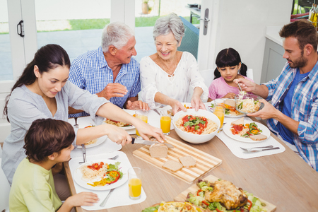 Smiling multi generation family having food at dining tableの写真素材