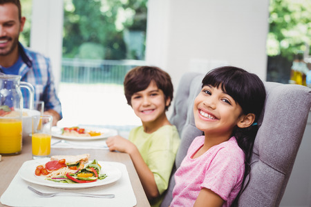 Portrait of smiling children sitting at dining tableの写真素材