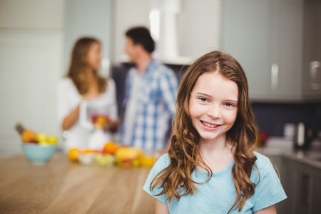 Portrait of smiling girl with parents standing in kitchenの写真素材