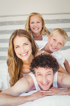 Portrait of smiling happy family resting on bed at homeの写真素材