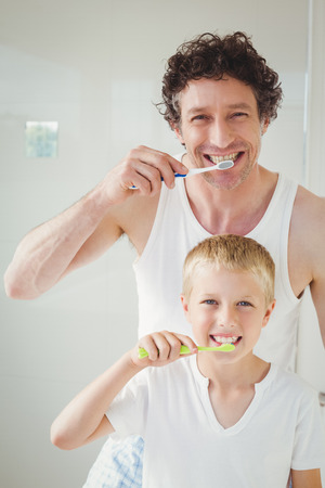Portrait of father and son brushing teeth at homeの写真素材