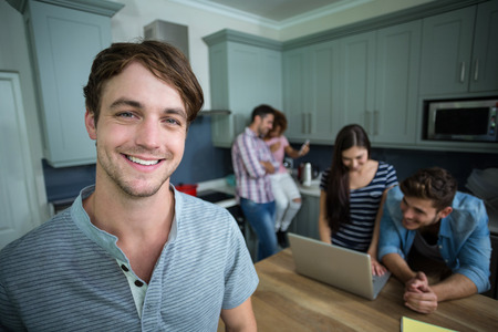 Close-up portrait of happy man with friends in background at homeの写真素材