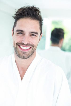 Portrait of happy handsome man against mirror at homeの写真素材