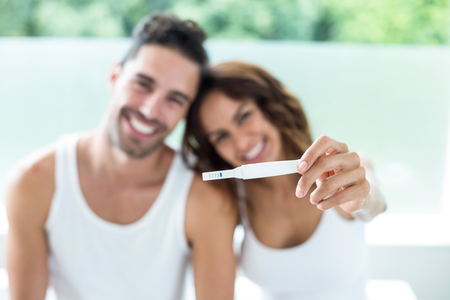 Portrait of happy couple showing pregnancy kitの写真素材