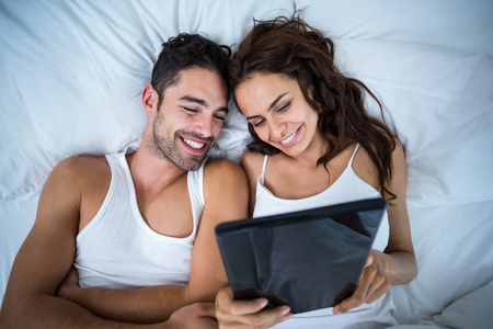 High angle view of smiling couple using digital tablet at homeの写真素材