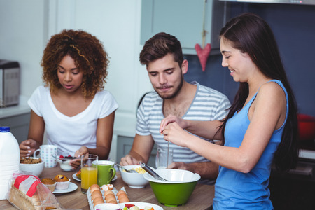 Smiling friends at breakfast table in homeの写真素材