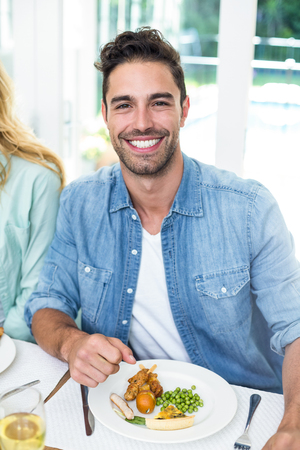 Portrait of happy man having food at dining tableの写真素材