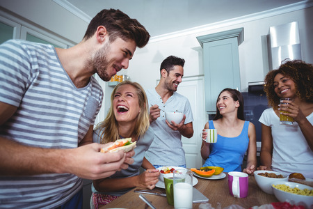 Cheerful friends having breakfast at table in kitchenの写真素材