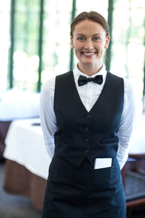 Happy waitress smiling at camera in a restaurant