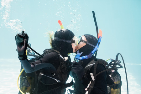 Couple kissing underwater while scuba diving in swimming poolの写真素材