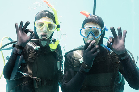 Couple on scuba training in swimming pool showing ok gestureの写真素材