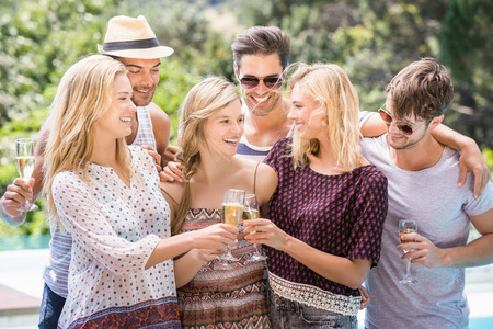 Group of happy friends toasting champagne glasses near poolの写真素材