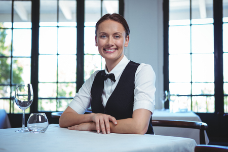 Waitress posing and sitting at the table in a restaurantの写真素材