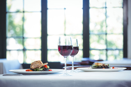 Squid ink spaghetti dish with basil for two with glasses of red wine in a restaurantの写真素材